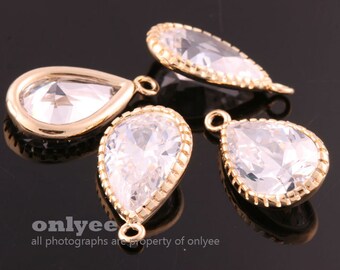 May include: Four gold teardrop-shaped pendants with clear crystal stones. Each pendant has a small loop at the top for attaching to a chain or other jewelry.