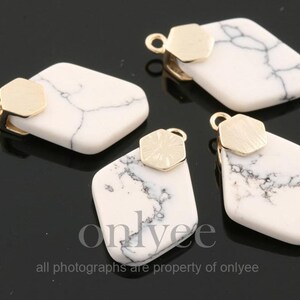 Puede incluir: Cuatro colgantes de mármol blanco y oro con forma geométrica. Los colgantes tienen un fondo de mármol blanco con vetas negras y un acento hexagonal dorado.
