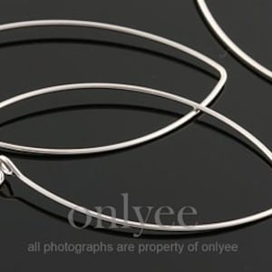 May include: A pair of silver oval-shaped hoop earrings. The earrings are made of thin wire and have a simple, minimalist design.