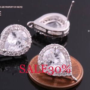 May include: Two silver teardrop-shaped earrings with clear cubic zirconia stones. The earrings have a halo setting and a post back.