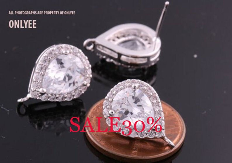 May include: Two silver teardrop-shaped earrings with clear cubic zirconia stones. The earrings have a halo setting and a post back.