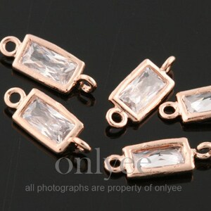 Op de afbeelding: Vijf roségouden metalen connector charms met heldere rechthoekige kristalaccenten. Elke bedel heeft twee lussen om aan sieraden te bevestigen.