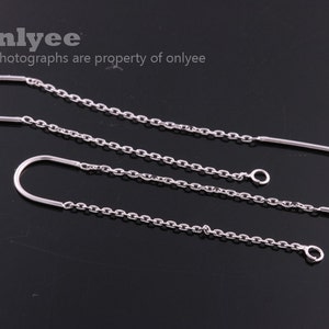 May include: A pair of silver chain earrings with a simple hoop design. The earrings are made of a delicate chain and have a small, round charm at the end.