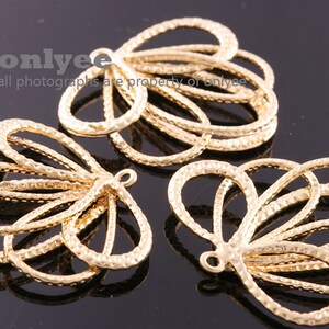 Puede incluir: Tres abalorios de metal de color dorado en forma de mariposa con una superficie texturizada. Cada abalorio tiene un bucle en la parte superior para sujetarlo a joyas u otras manualidades.