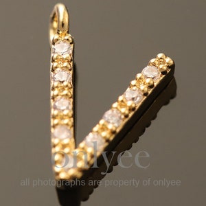 May include: Gold letter V charm with clear rhinestones. The charm is a pendant for jewelry making.