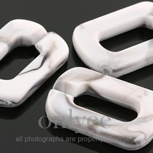 May include: Three white and gray marbled plastic rectangular connector links. The links have a smooth, rounded surface and a rectangular hole in the center.