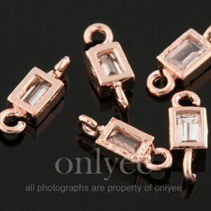 Op de afbeelding: Vijf roségouden metalen connector charms met heldere rechthoekige kristal accenten. Elke charm heeft een lus aan beide uiteinden om aan sieraden te bevestigen.