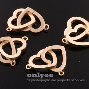 May include: Four gold-toned metal double heart charms with a smooth finish. Each charm has two interlocking heart shapes.