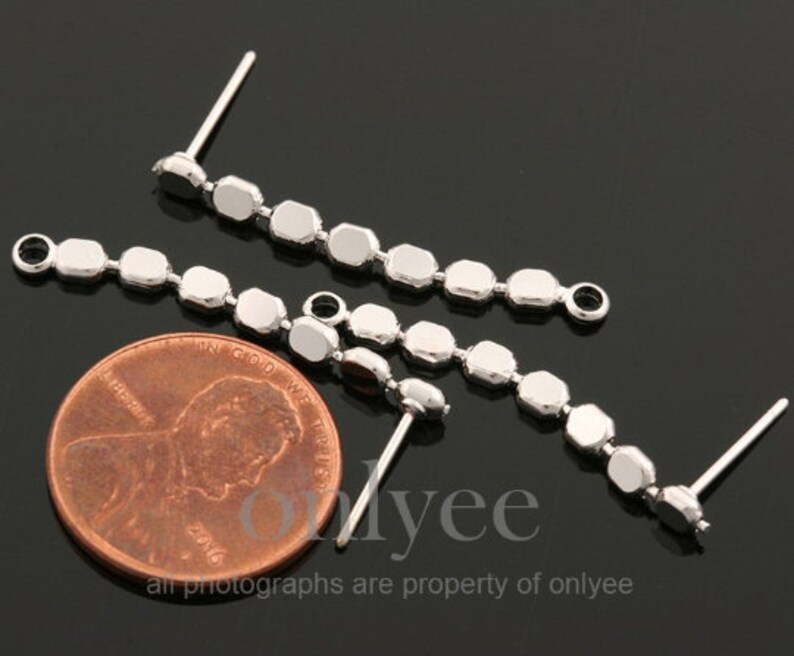 May include: Three silver earring findings with a chain of small, round, silver beads. The findings have a loop at the top and a post at the bottom.