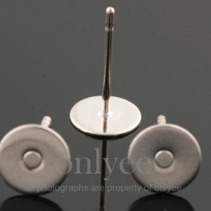 May include: Three silver earring posts with flat round backs. The posts are made of metal and have a smooth finish.