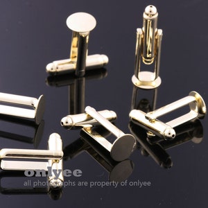May include: Six gold-toned cufflinks with round, flat tops. The cufflinks are arranged on a black surface.