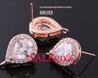 May include: A pair of rose gold teardrop earrings with clear cubic zirconia stones. The earrings have a post back and a small loop on the side.