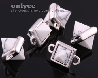 May include: Five silver and white pyramid-shaped charms with a loop on each side. The charms are made of metal and have a white stone in the center.