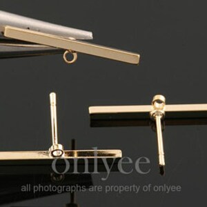 May include: Gold bar earring with a post and a loop on the end. The bar is about 1 inch long.