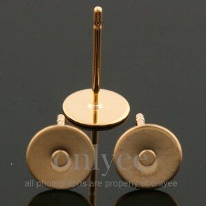 May include: Three gold-colored earring posts with flat round backs. The posts are made of metal and have a smooth finish.