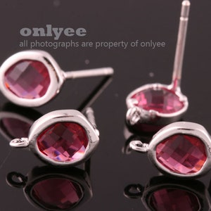 May include: Four silver earring posts with pink crystal accents. The crystals are faceted and have a square shape.
