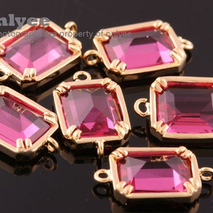 May include: Six pink glass rectangular connector charms with gold metal frames and loops. The charms are approximately 1 inch long and 0.5 inches wide.