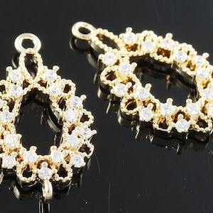 May include: Two gold-tone metal earring findings with a teardrop shape and a clear rhinestone design.