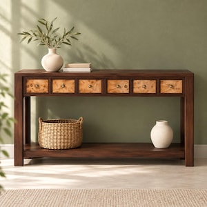 May include: A rectangular dark wood console table featuring six drawers with light-colored burl wood fronts and small round knobs. The table includes a lower shelf holding a woven wicker basket and a white ceramic vase.