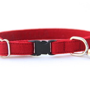 May include: Red felt cat collar with a black plastic buckle and a silver bell.