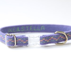 May include: Purple cat collar with a pink and green patterned trim and a clear plastic buckle. The collar is personalised with the name "KEASTELLA".