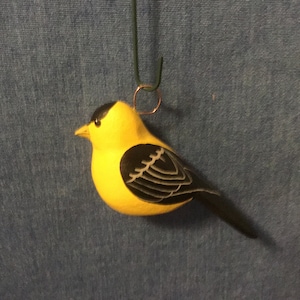 May include: A yellow and black wooden bird ornament with a wire loop for hanging.