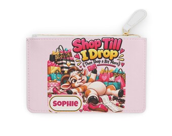 May include: A light pink rectangular zippered pouch featuring a cartoon goat lying amidst shopping bags and shoes. The text reads Shop Till I Drop (Then Shop a Bit More) and the name Sophie in a yellow-bordered box with pink lettering.