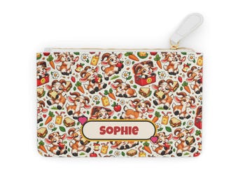 Può includere: Una pochette rettangolare con chiusura a zip caratterizzata da un motivo ripetuto di caprette, carote, succhi di frutta, panini e mele. Al centro, un'etichetta orizzontale con sfondo crema e bordo rosso riporta il nome SOPHIE.