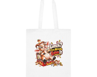 Può includere: Una borsa tote bianca con una capra a cartoni animati seduta dentro un portapranzo rosso aperto. La capra ha un torsolo di mela sulla testa. Il testo recita: Lunch? I've Already Eaten It, con il sito web SillyGoatGoods.com in basso a destra.