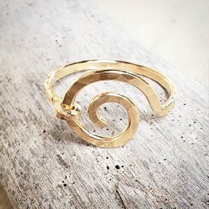 May include: A gold ring with a hammered finish and a spiral design. The ring is simple and elegant.