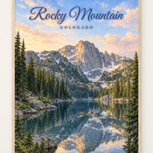 Könnte beinhalten: Ein gerahmter Wandkunstdruck mit einer Landschaft der Rocky Mountain in Colorado. Die Szene zeigt einen zerklüfteten, schneebedeckten Berggipfel, der sich in einem ruhigen See spiegelt, umgeben von dichten Nadelbäumen unter einem Abendhimmel.
