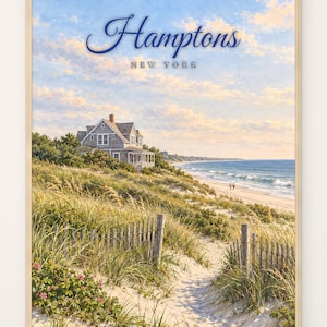May include: A framed wall art print featuring a coastal landscape with a shingled house on a grassy dune, a sandy path leading to the beach, and the text Hamptons New York in blue script and block lettering against a soft blue sky with clouds.