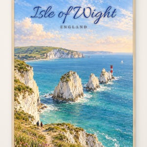 Op de afbeelding: Een ingelijste reisposter van het Isle of Wight, Engeland. De afbeelding toont witte krijtrotsen, turquoise zeewater en een rood-witte vuurtoren. Twee kleine figuren staan op een met gras begroeid klifpad onder een blauwe lucht met wolken.