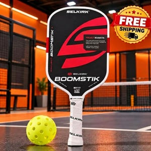 May include: A black and white Selkirk Project Boomstik pickleball paddle with a large red graphic design and white grip tape, accompanied by a bright yellow perforated pickleball. The paddle features the text Selkirk and Boomstik.