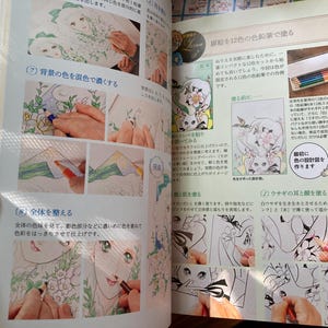 May include: A book page with illustrations and instructions for coloring. The page features step-by-step guides with images of hands coloring drawings of anime-style characters with colored pencils. Text in Japanese accompanies the images.
