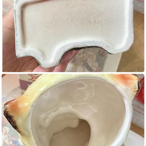 May include: A vintage ceramic planter, featuring a cream-colored interior and a light green and yellow exterior. The planter has a rectangular base with a curved design and a detailed top. The interior is smooth, while the exterior has a textured finish.