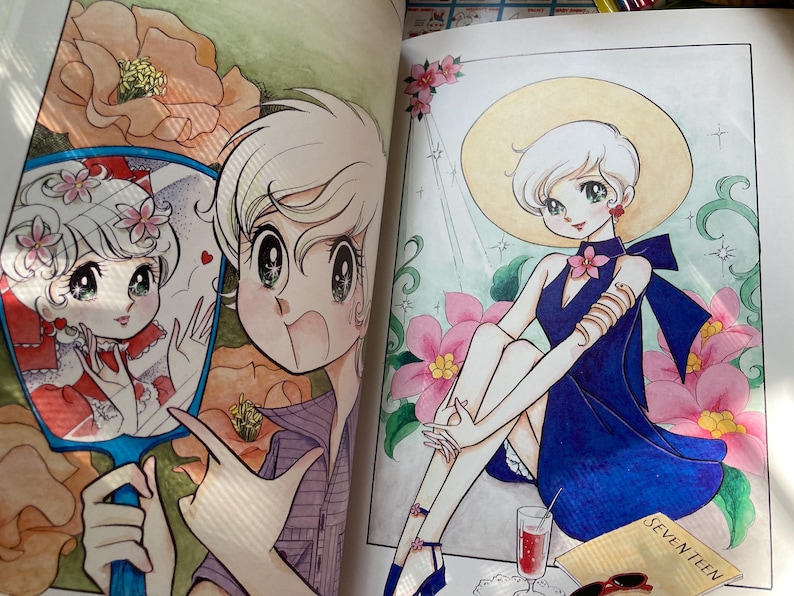 May include: A colorful illustration from a coloring book featuring a young person with white hair. The person is wearing a blue dress and a wide-brimmed hat, surrounded by pink flowers. A mirror shows a reflection of the person.