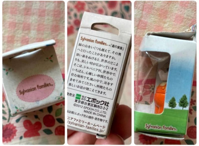 May include: A set of Sylvanian Families miniature figurines in their original packaging. The boxes feature text in Japanese and English, with a pink oval logo. One box shows a small orange figure.
