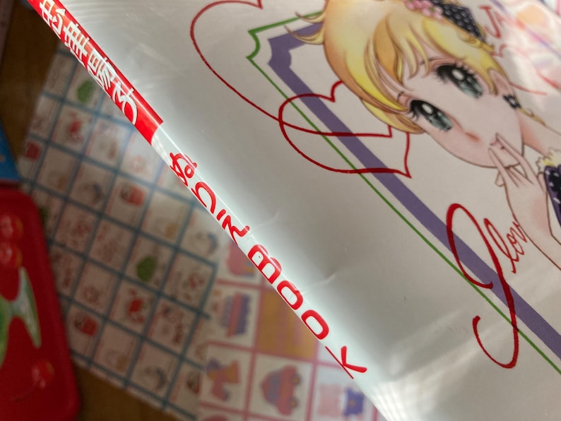 May include: A book cover featuring a manga-style illustration of a young woman with blonde hair and blue eyes. The cover has a white background with red and purple accents, and the word "Love" is written in a cursive font.