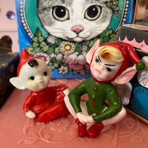 Figura de cerámica vintage de los años 1860: pequeña figura de elfo rojo y verde sentado, estilo hada, de cerámica kitsch procedente de Japón.