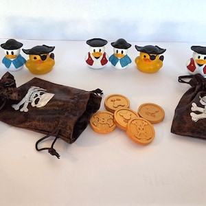 May include: A collection of nine small rubber ducks wearing black pirate hats, with some wearing red or blue vests and others featuring eye patches. Three brown drawstring pouches with white skull and crossbones prints and five gold coins.