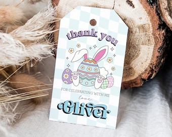 May include: A white thank you tag with a blue and white checkered background. It features a cartoon bunny wearing a pastel egg with a pink bow. The text reads "thank you for celebrating with me love, Oliver".