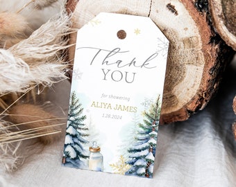 Könnte beinhalten: Ein rechteckiger Geschenkanhänger aus Papier mit einem Loch oben, der eine winterliche Waldszene in Aquarelloptik mit schneebedeckten Tannen, einem Babyfläschchen und goldenen Schneeflocken zeigt. Der Text lautet Thank YOU for showering ALIYA JAMES 1.28.2024.