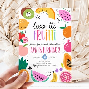 Puede incluir: Una tarjeta de invitación colorida con un tema de frutas. La tarjeta dice "two-tti FRUITTI" y "AVA IS TURNING 2". La invitación incluye una fecha y hora, dirección e información de contacto.