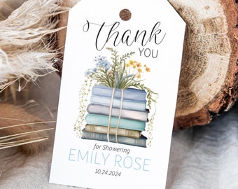 May include: A white thank you tag with a stack of blue and green books with a floral arrangement on top. The text on the tag reads "Thank You for Showering Emily Rose 10.24.2024".