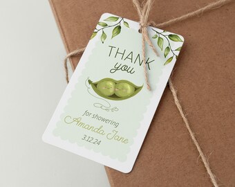 Op de afbeelding: Bedankt voor het vieren van de baby shower voor Amanda Jane op 3.12.24.  Groene peul met twee erwten erin.  Wit en groen baby shower-cadeautje-etiket met groene bladeren.