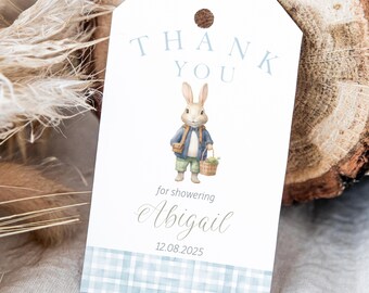May include: A white thank you tag with a blue and white plaid border. The tag features a cartoon bunny holding a basket of flowers. The text on the tag reads "Thank You" and "for showering Abigail 12.08.2025".