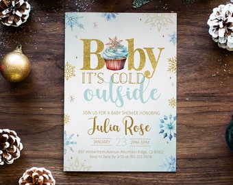Op de afbeelding: Een baby shower uitnodiging met een blauw en wit winterthema. De uitnodiging heeft een cupcake met een sneeuwvlok erop en de tekst "Baby It's Cold Outside". De uitnodiging is voor Julia Rose en is gepland voor 23 januari van 14:00 tot 17:00 uur.