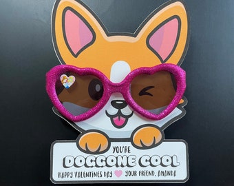 May include: A corgi-shaped Valentine's Day card with pink heart-shaped sunglasses. The card reads "You're Doggone Cool" and includes the text "Happy Valentine's Day" and "Your Friend, Amanda". The card is a printable, editable file.