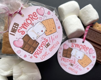 May include: Two pink and white printable gift tags with a s'more theme. The tags feature a cartoon illustration of a marshmallow, chocolate bar, and graham cracker. The text on the tags reads "I need s'more friends like you, love, Amelia".